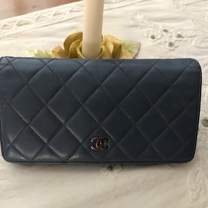 May include: A dark blue quilted leather wallet with a silver Chanel logo.