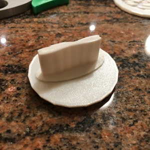 Può includere: Tagliapasta in plastica bianca con un designo in rilievo. Il tagliapasta ha la forma di un cerchio con un cerchio più piccolo al centro.