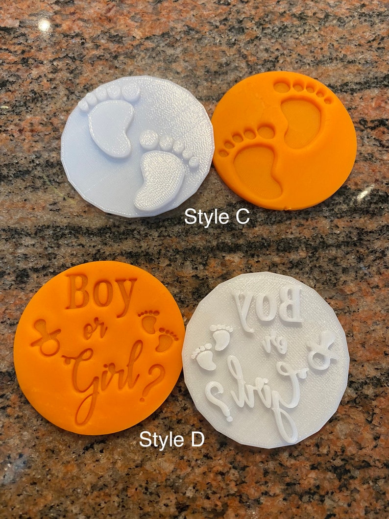 Pode incluir: Dois conjuntos de cortadores de biscoitos, um branco e um laranja. O conjunto branco tem duas pegadas e o texto "Boy or Girl?" O conjunto laranja tem duas pegadas e o texto "Boy or Girl?"