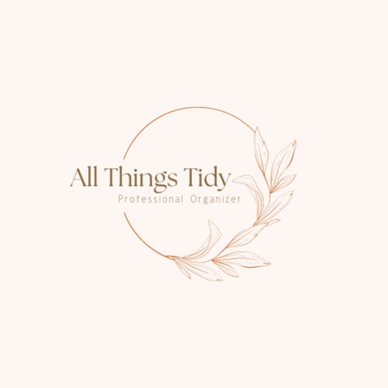 Op de afbeelding: Logo voor "All Things Tidy, Professional Organizer" in zacht beige. De tekst is in een schreefletter, omgeven door een dunne, koperkleurige cirkel en bloemelementen.