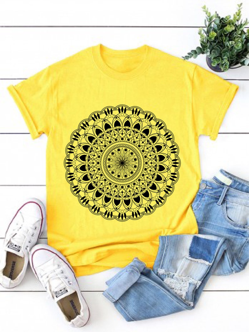 Op de afbeelding: Een geel T-shirt met een zwart mandala-ontwerp. Het shirt is casual en comfortabel, perfect voor dagelijks gebruik.