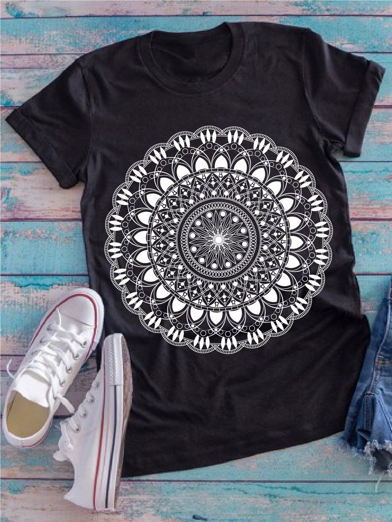 Op de afbeelding: Zwart T-shirt met een wit mandala-ontwerp. De mandala is een cirkelvormig patroon met ingewikkelde details.