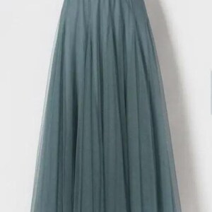 May include: A long, teal-coloured skirt. The skirt is made from a sheer, layered fabric, possibly tulle, creating a full, A-line shape. It has an elasticated waistband. The skirt is suitable for special occasions or as a fashion statement. The length is approximately 100 cm.