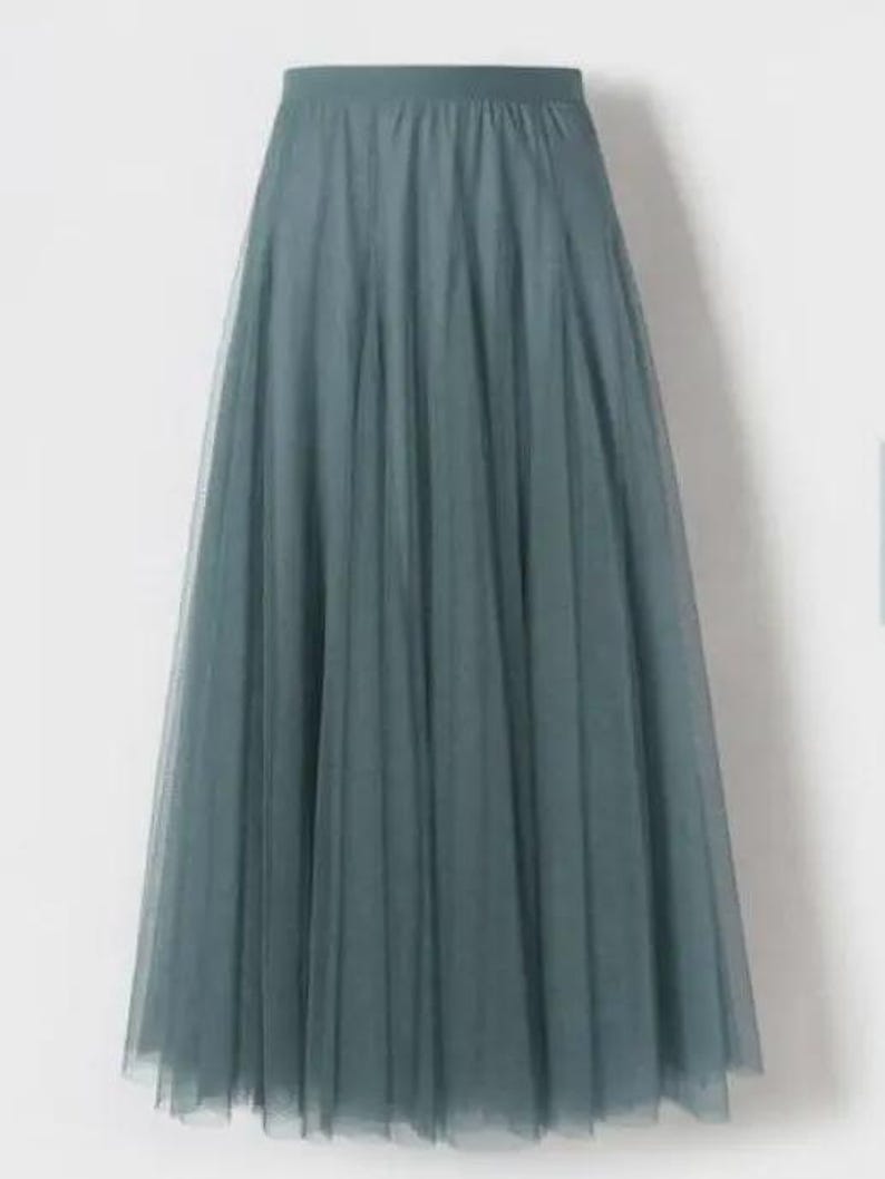 May include: A long, teal-coloured skirt. The skirt is made from a sheer, layered fabric, possibly tulle, creating a full, A-line shape. It has an elasticated waistband. The skirt is suitable for special occasions or as a fashion statement. The length is approximately 100 cm.