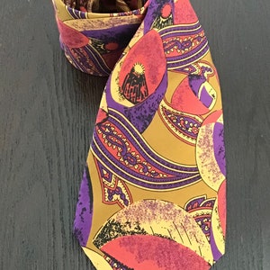 May include: A silk tie with a paisley pattern in shades of gold, purple, pink, and black.