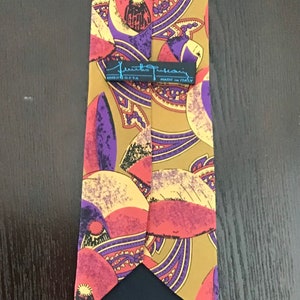 May include: A brown silk tie with a paisley pattern in shades of purple, pink, and yellow. The tie has a black label that reads "Frank  Frasconi 100% Seta Made in Italy".