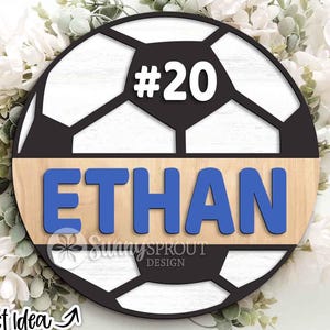 May include: A wooden soccer ball design with the name "ETHAN" in blue letters and the number "20" in white. The design is set against a light wood background and a black soccer ball pattern. The words "Sunny Sprout Design" are also visible.