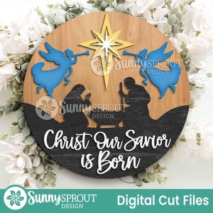 May include: A round wooden sign with a Christmas theme. The sign features a star, angels, and silhouettes of figures. The text "Christ Our Savior is Born" is displayed in white. The sign also includes the text "Digital Cut Files".