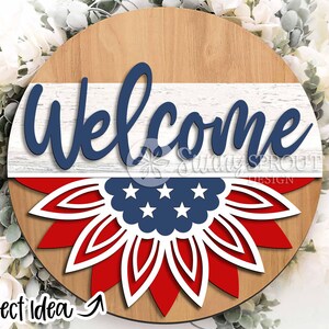 May include: A round wooden sign with a red, white, and blue mandala design. The sign says "Welcome" in blue lettering on a white background.