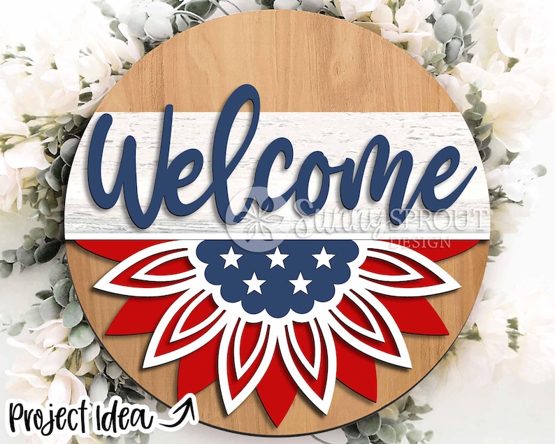 May include: A round wooden sign with a red, white, and blue mandala design. The sign says "Welcome" in blue lettering on a white background.