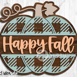 Peut inclure: Une pancarte en bois en forme de citrouille avec un motif à carreaux dans les tons bleu sarcelle et marron. La pancarte indique "Happy Fall" en lettres orange pêche.