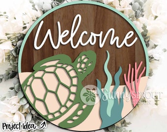 May include: A round wooden sign with the word "Welcome" in white script. A green sea turtle with a pink shell is in the bottom half of the sign, surrounded by green seaweed and pink coral.