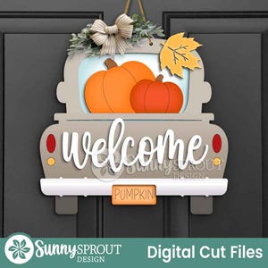 Può includere: Un cartello di benvenuto in legno a forma di camion, con due zucche arancioni nel cassone. Il cartello ha una combinazione di colori beige e bianco, con la parola "welcome" in corsivo. Un piccolo cartello recita "pumpkin". Un fiocco e una foglia accentuano la parte superiore.