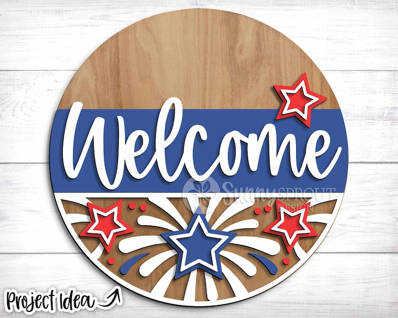 May include: A wooden round welcome sign with a blue and white striped band. The sign features the word "Welcome" in white lettering and a red, white, and blue firework design.