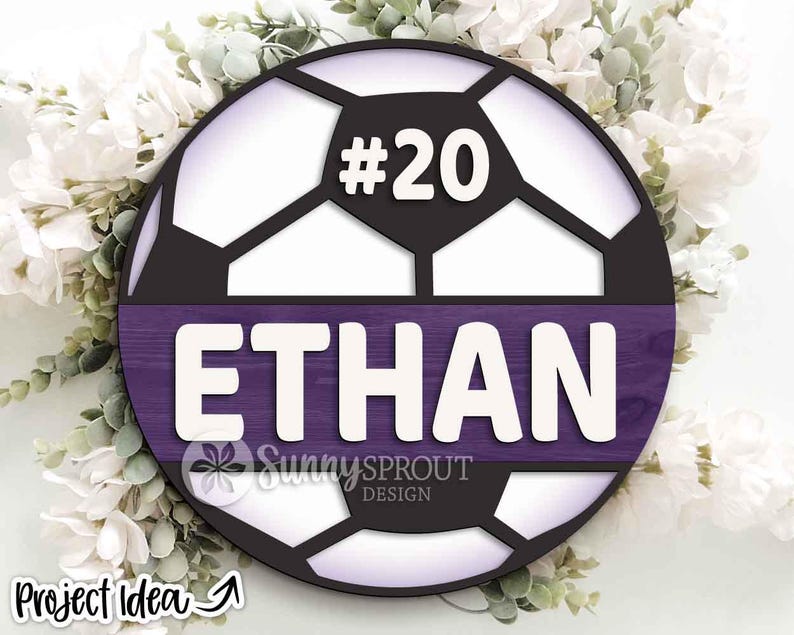 May include: A circular soccer ball design featuring the name "ETHAN" in white block letters on a purple panel. The number "#20" is above the name. The design includes the text "Sunny Sprout Design" and "Project Idea".