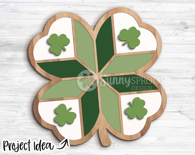 May include: Wooden four-leaf clover decoration with a light brown border. The clover is divided into sections of white, light green, and dark green. Each leaf has a green shamrock. The text "Project Idea" is at the bottom.