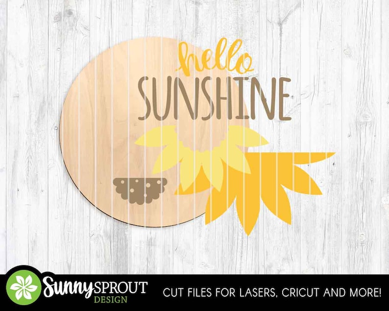 May include: A circular wooden sign featuring the words "hello SUNSHINE" in yellow and brown. A yellow and brown sunflower design is on the right. The sign is set against a white wooden backdrop.