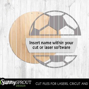 May include: A wooden soccer ball design with a circular wooden background. The design includes a soccer ball outline with a space for a name. Text on the design reads: "Insert name within your cut or laser software."