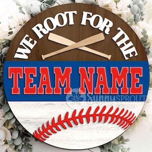 以下が含まれることがあります： 「WE ROOT FOR THE」の白文字と交差した野球バットが描かれた丸い木製サイン。その下に、赤で「TEAM NAME」と書かれた青い部分があります。下部には赤い野球のステッチデザインがあります。