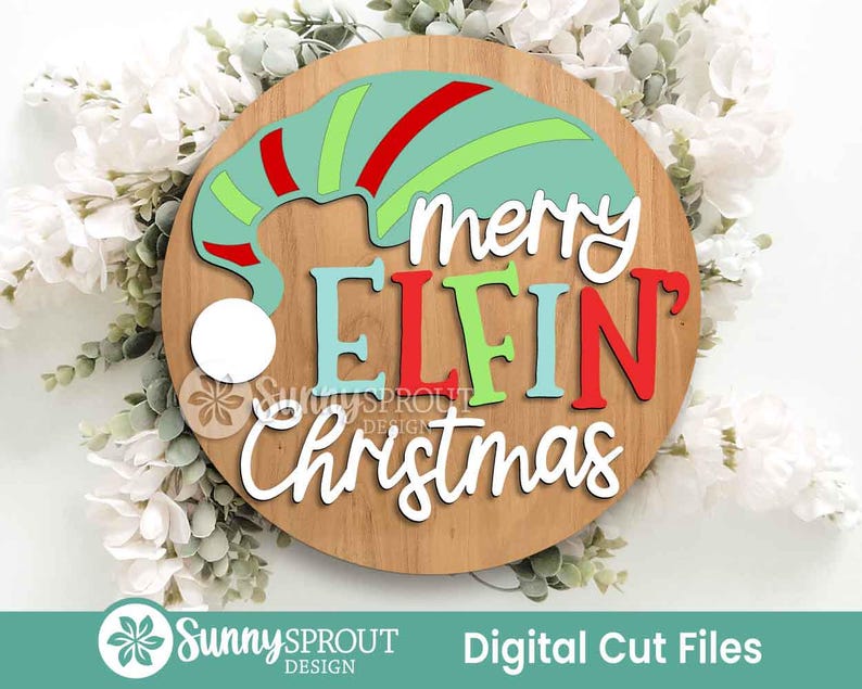 May include: A circular wooden sign featuring a layered design with a teal, red, and lime green elf hat and the text "merry ELFIN Christmas" in white, teal, and red lettering. The sign includes a white circular pom-pom accent on the hat.