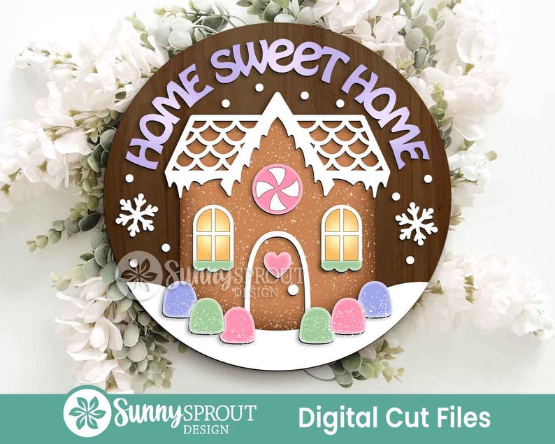 May include: A round wooden sign with a gingerbread house design. The sign has the words "HOME SWEET HOME" in purple letters. The gingerbread house has white icing and colorful candies. The sign is surrounded by white flowers and greenery.