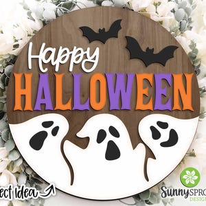 May include: A round wooden sign with the words "Happy Halloween" in orange and purple letters. Three white ghosts with black eyes are on the bottom of the sign.
