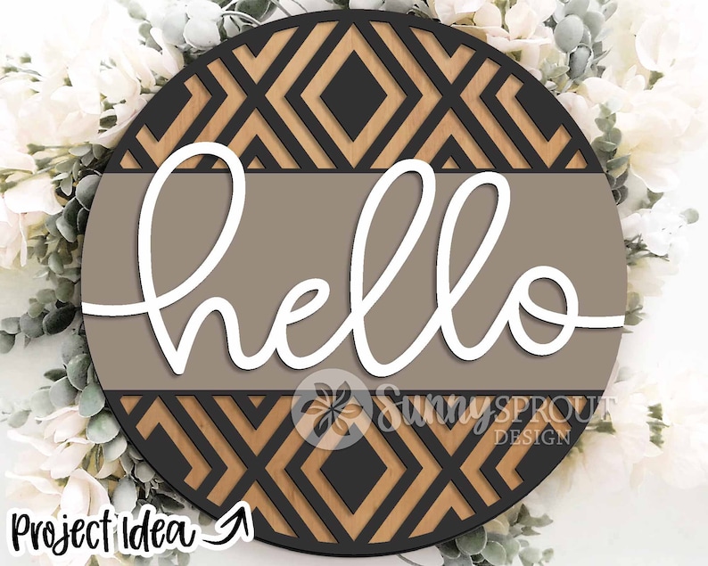 May include: A round wooden sign with a geometric pattern in black and brown. The word "hello" is written in white cursive on a brown background.