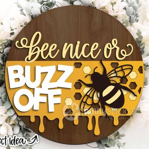May include: A round wooden sign with a yellow and brown background. The sign says "Bee nice or buzz off" with a black and yellow bee illustration.
