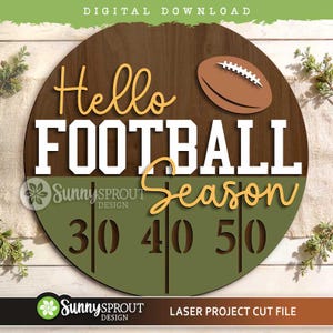 Peut inclure: Un panneau circulaire en bois avec une moitié supérieure en grain de bois brun et une moitié inférieure vert olive. Le texte indique Hello FOOTBALL Season en lettres blanches et jaunes. Un ballon de football brun et les chiffres 30 40 50 sont visibles.