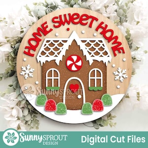 K&ouml;nnte beinhalten: Runder Holzschild mit Lebkuchenhaus-Design. Das Schild tr&auml;gt die roten Worte "HOME SWEET HOME". Das Lebkuchenhaus ist braun mit wei&szlig;em Zuckerguss und S&uuml;&szlig;igkeiten-Akzenten. Das Schild hat auch Schneeflocken und den Text "Digital Cut Files".