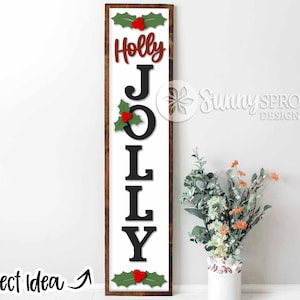 May include: A white wooden sign with the word "HOLLY JOLLY" in black letters. The letters are decorated with red berries and green holly leaves. The sign has a brown wooden frame.