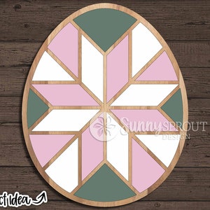 May include: A round wooden craft project with a geometric design. The design features pink and green triangles arranged in a starburst pattern.