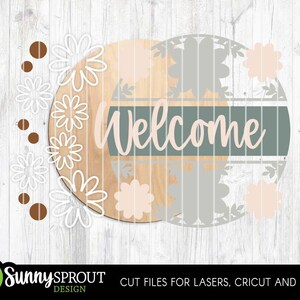 May include: A round wooden sign with the word "Welcome" in cursive, set against a light green and tan background. The sign is decorated with white and peach-colored flower cutouts and brown dots. The Sunny Sprout Design logo is at the bottom.
