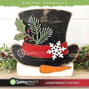 May include: A black top hat decoration with a distressed finish, featuring a red band, a white snowflake cutout, green holly leaves with red berries, and an orange carrot nose. The text "DIGITAL DOWNLOAD" and "SUNNY SPROUT DESIGN" are visible.