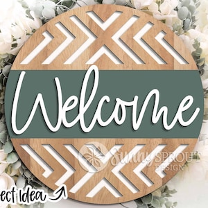 May include: A round wooden sign with a chevron pattern and a green band that says "Welcome".