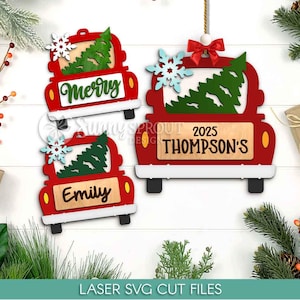 Könnte beinhalten: Rote Weihnachts-LKW-Ornamente aus Holz mit weißen Akzenten, schwarzen Rädern und einem grünen Baum. Eines zeigt "Merry", ein anderes "Emily" und das dritte "2025 Thompson's". Jedes hat eine Schneeflocke.