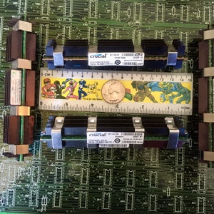 May include: Two black Crucial brand RAM modules with silver clips are installed on a green circuit board. The modules have the text "Crucial" and "BT128T16933.SL.16" printed on them.