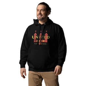 May include: Black hooded sweatshirt with a front graphic. The graphic features the word "UNITED" in gold, the number "1878" in red, and the words "OLD TRAFFORD" in gold. Above the word "UNITED" are three red stars.