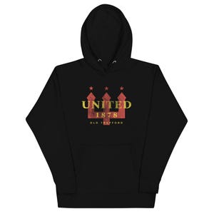 May include: Black hooded sweatshirt with a front graphic. The graphic features the word "UNITED" above the number "1878" and the words "OLD TRAFFORD" in a distressed style. The graphic is in red and gold.