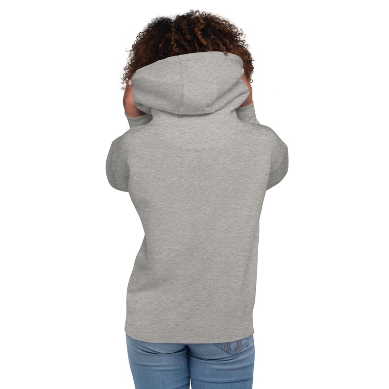 May include: A heather gray hoodie with a drawstring hood. The back view of the hoodie is shown, with the hood up. The hoodie is made of a soft material and has a relaxed fit. The person is wearing blue jeans.