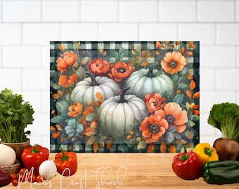 May include: A kitchen cutting board with a black and white checkered pattern features a watercolor painting of white pumpkins with orange and red flowers.