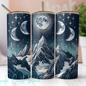 May include: A stainless steel tumbler with a celestial design featuring a full moon, crescent moons, stars, and snow-capped mountains. The tumbler has a dark blue background with a gold-colored lid and a straw. The text "Macs Craft Shack" is at the bottom.