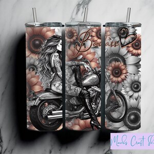 May include: Three stainless steel tumblers with lids and straws. Each tumbler features a black and white illustration of a woman on a motorcycle, surrounded by sunflowers. The text "Bad Ass" is displayed on one tumbler.