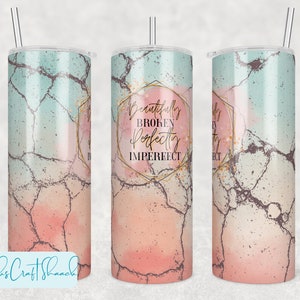 May include: A stainless steel tumbler with a pink and blue marble design and gold accents. The tumbler has a straw and the text "Beautifully Broken Perfectly Imperfect" is printed on the front.