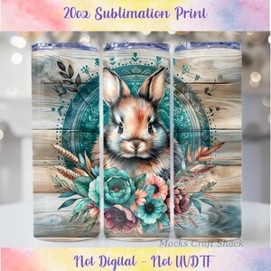 May include: A 20oz sublimation print tumbler featuring a detailed illustration of a rabbit with floral accents. The design includes a teal mandala, flowers, and wheat against a wood-grain background. The text "20oz Sublimation Print" is at the top.