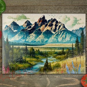 May include: A glass cutting board with a watercolor painting of a mountain range with a river flowing through a valley. The mountains are blue, green, and white, and the river is blue. The valley is green and brown.