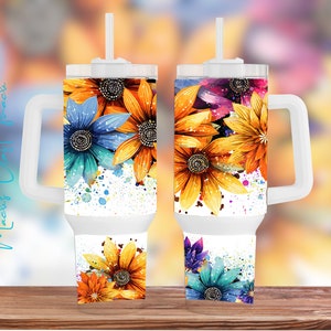 May include: Two white travel mugs with a floral design featuring blue, yellow, orange, and pink flowers with a watercolor effect. The mugs have a handle and a lid with a straw.