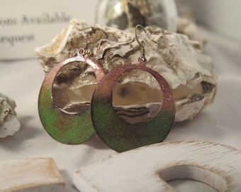 May include: A pair of green and pink ombre hoop earrings with a textured finish. The earrings are made of metal and have a simple, elegant design.