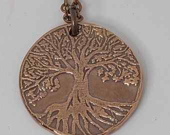 May include: A copper necklace with a round pendant featuring a detailed tree of life design.
