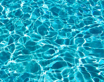 Può includere: Primo piano di una piscina blu con acqua increspata. L'acqua è limpida e riflette la luce del sole, creando un effetto scintillante.